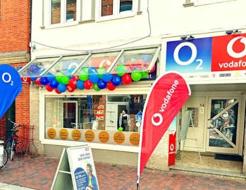 Mobilfunkladen mit O2- und Vodafone-Logo, bunte Luftballons und Werbeaufsteller vor dem Geschäft.