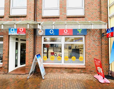 Handyladen mit O2-, Vodafone- und Mobilcom-Debitel-Logos an roter Backsteinfassade